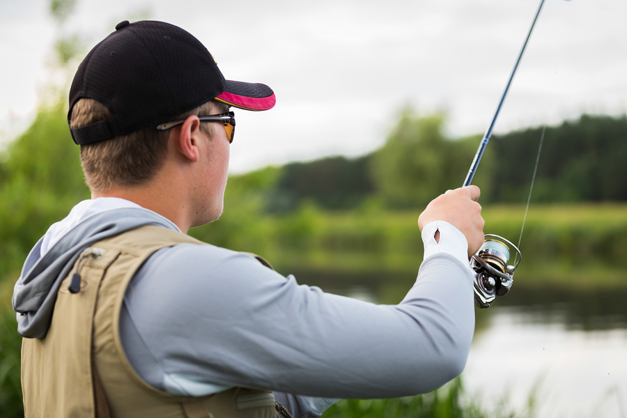 Fishing in river.A fisherman with a fishing rod on the river bank. Man fisherman catches a fish.Fishing, spinning reel, fish, Breg rivers. - The concept of a rural getaway. Article about fishing.