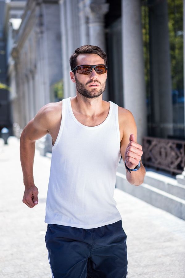 Handsome athlete with sunglasses jogging in the city